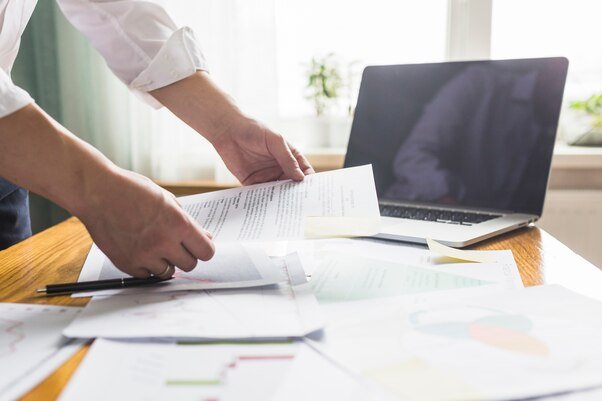 businessperson-s-hand-holding-document-wooden-desk_23-2147838593